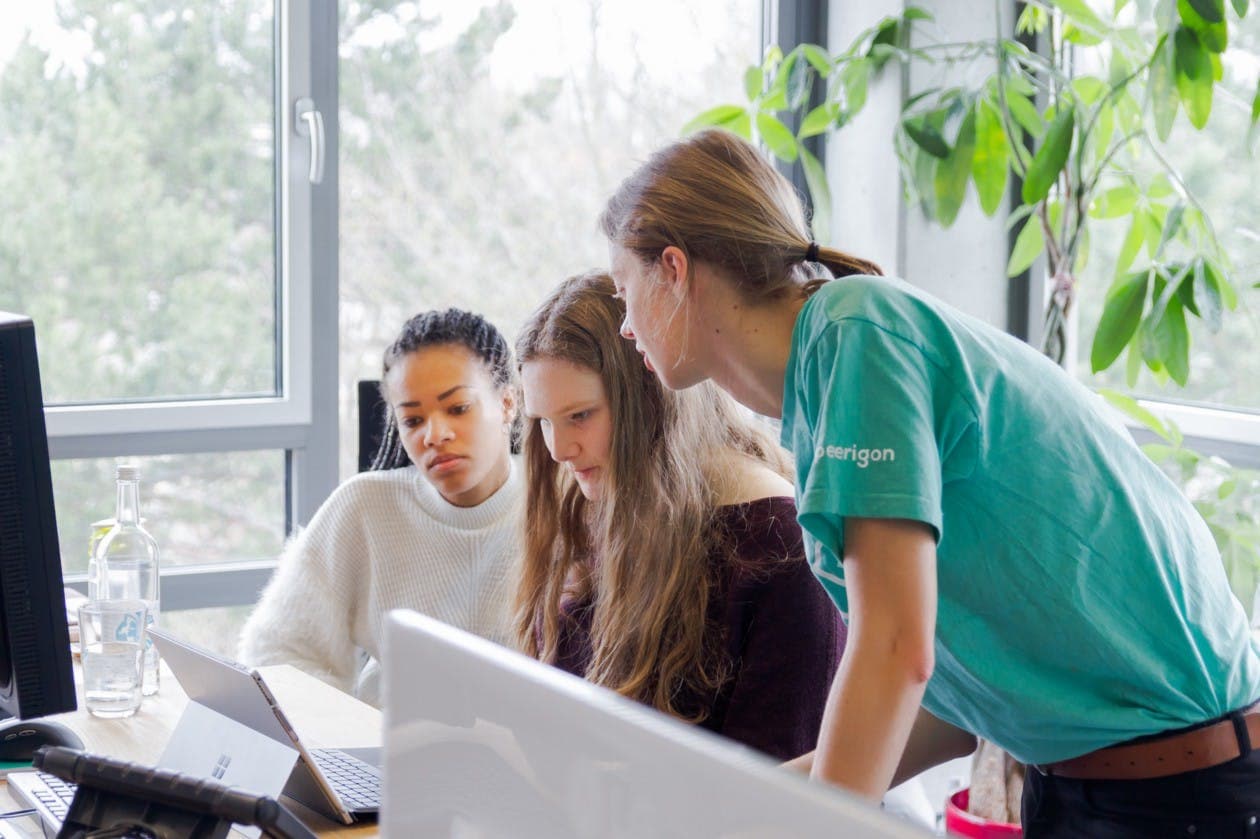 three women in front of computers talking to each other